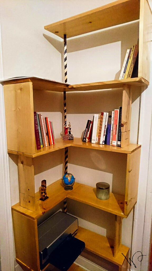 Bibliothèque d'angle en bois avec des livres et objets décoratifs